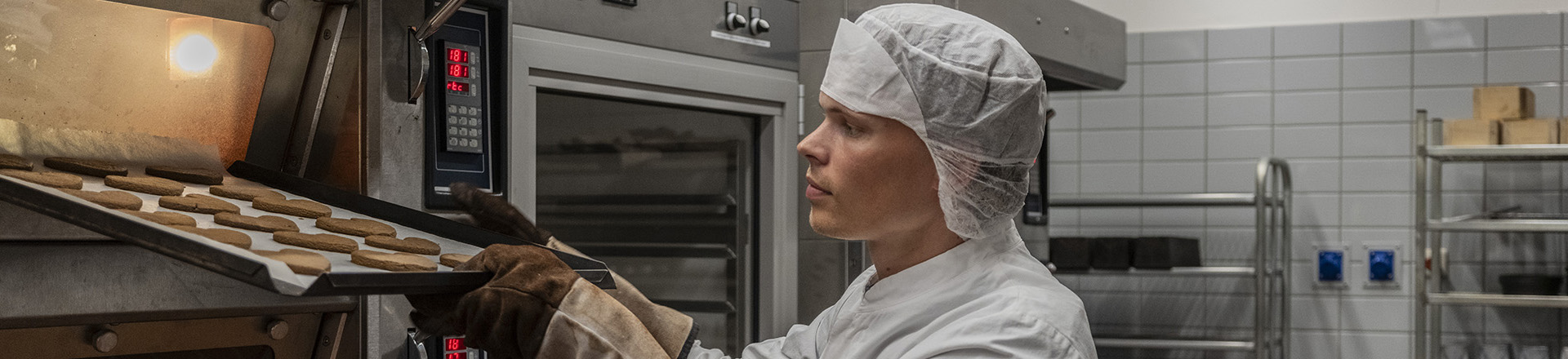 Student haalt versgebakken koekjes uit de oven.