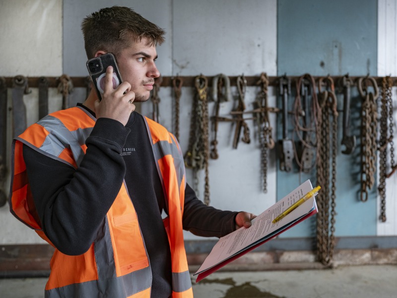 jongen aan de telefoon met veiligheidshesje
