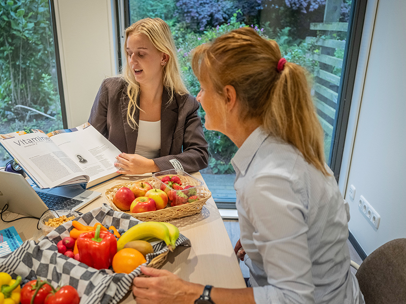 twee meisjes zitten aan tafel met fruit voor zich