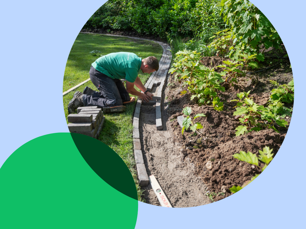 jongen legt tuin aan met behulp van stenen om een groenperkje