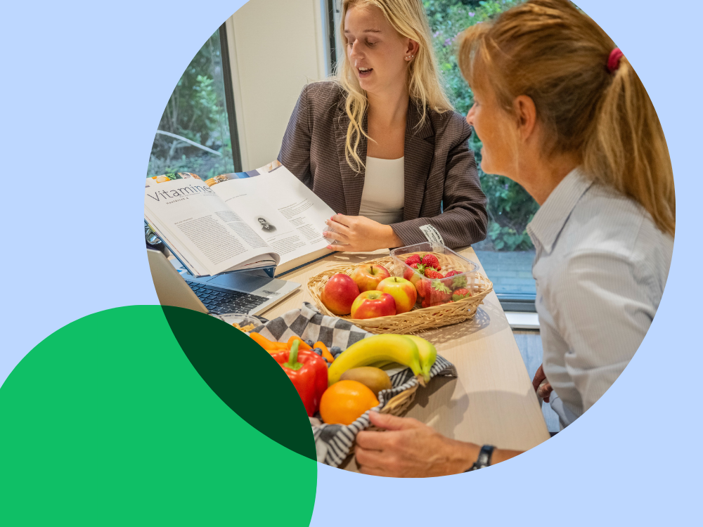 TWEE MEISJES ZITTEN AAN TAFEL MET FRUIT VOOR ZICH OP TAFEL